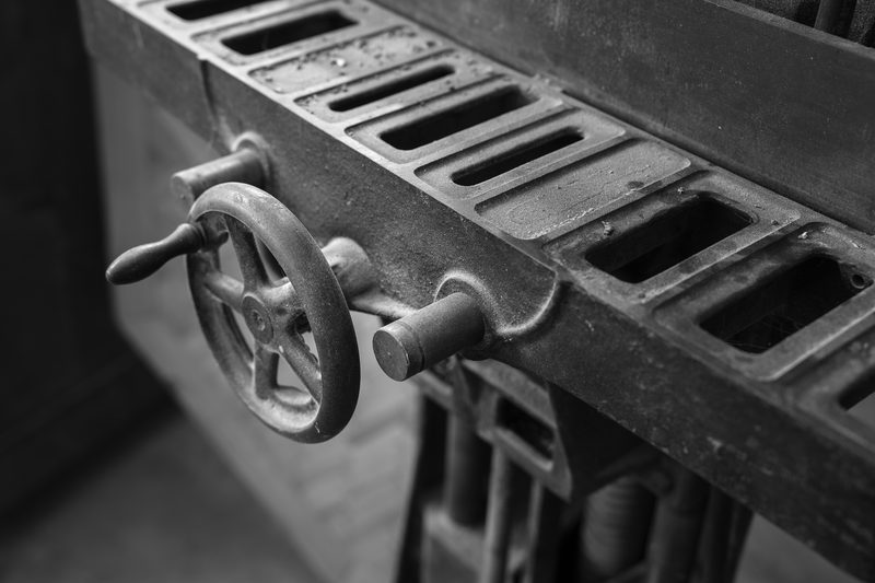 Close view of a cast-iron handwheel on the slotted bed of an old woodworking machine.